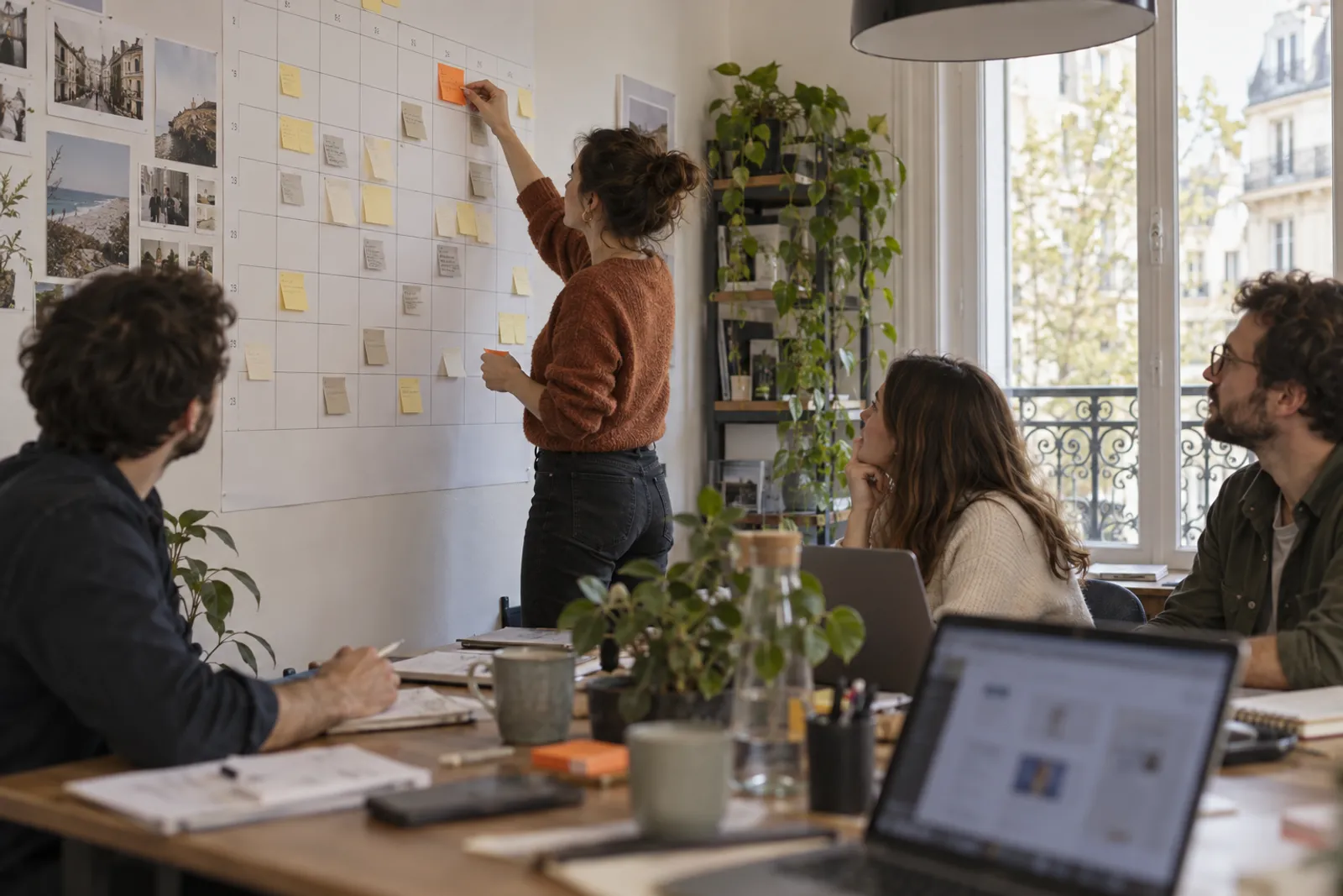 Une salariée accroche une note sur un calendrier mural déjà couvert de dizaines de notes, une par article prévu.